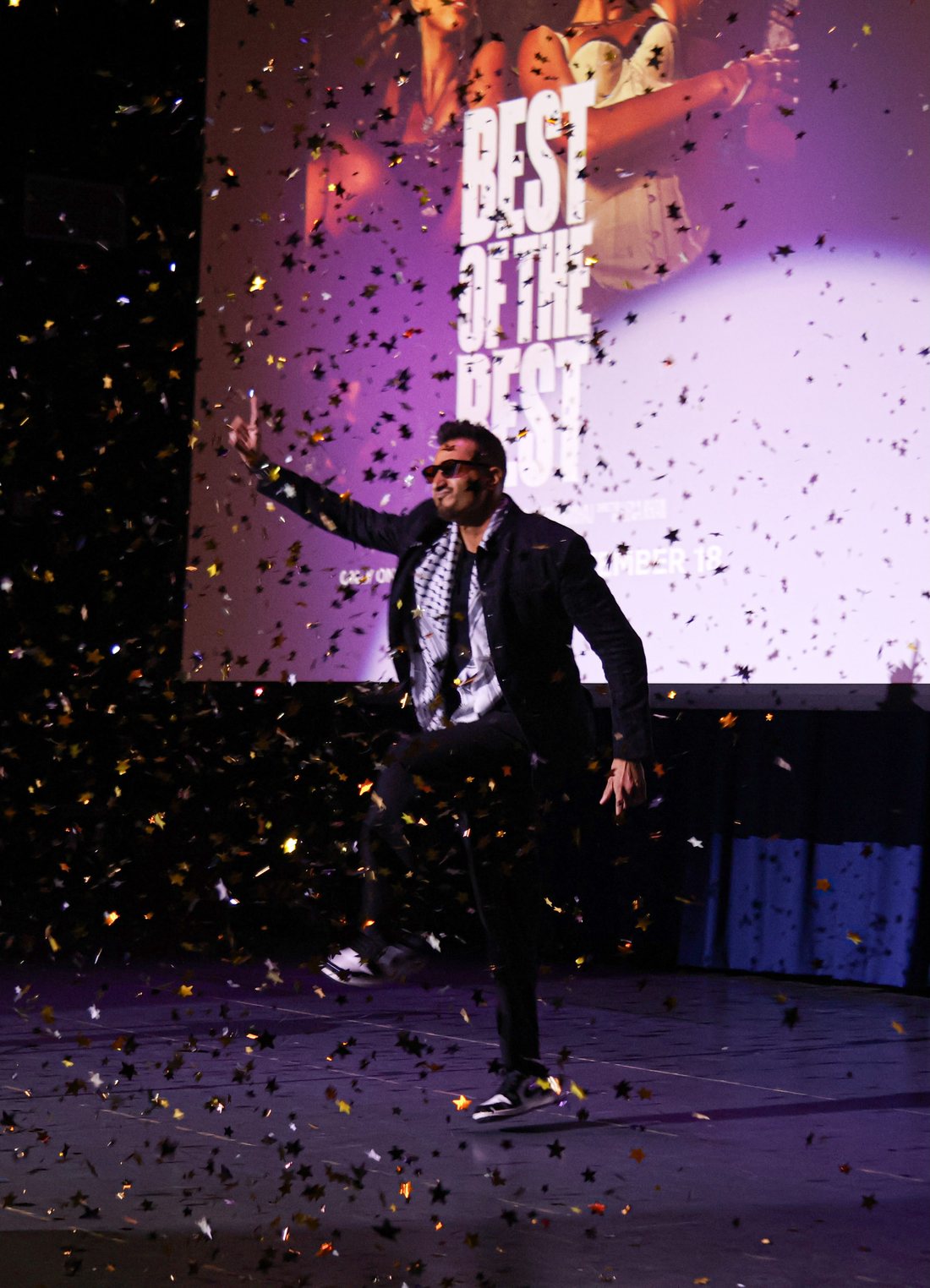 Asim Khan dancing on stage in sunglasses as confetti falls