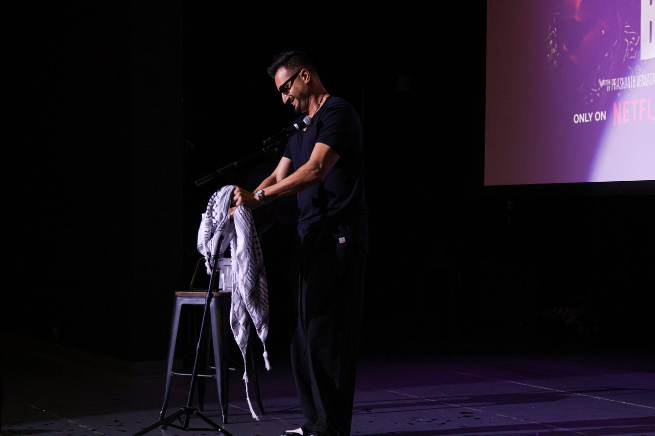 Asim Khan at the microphone stand on a dark stage
