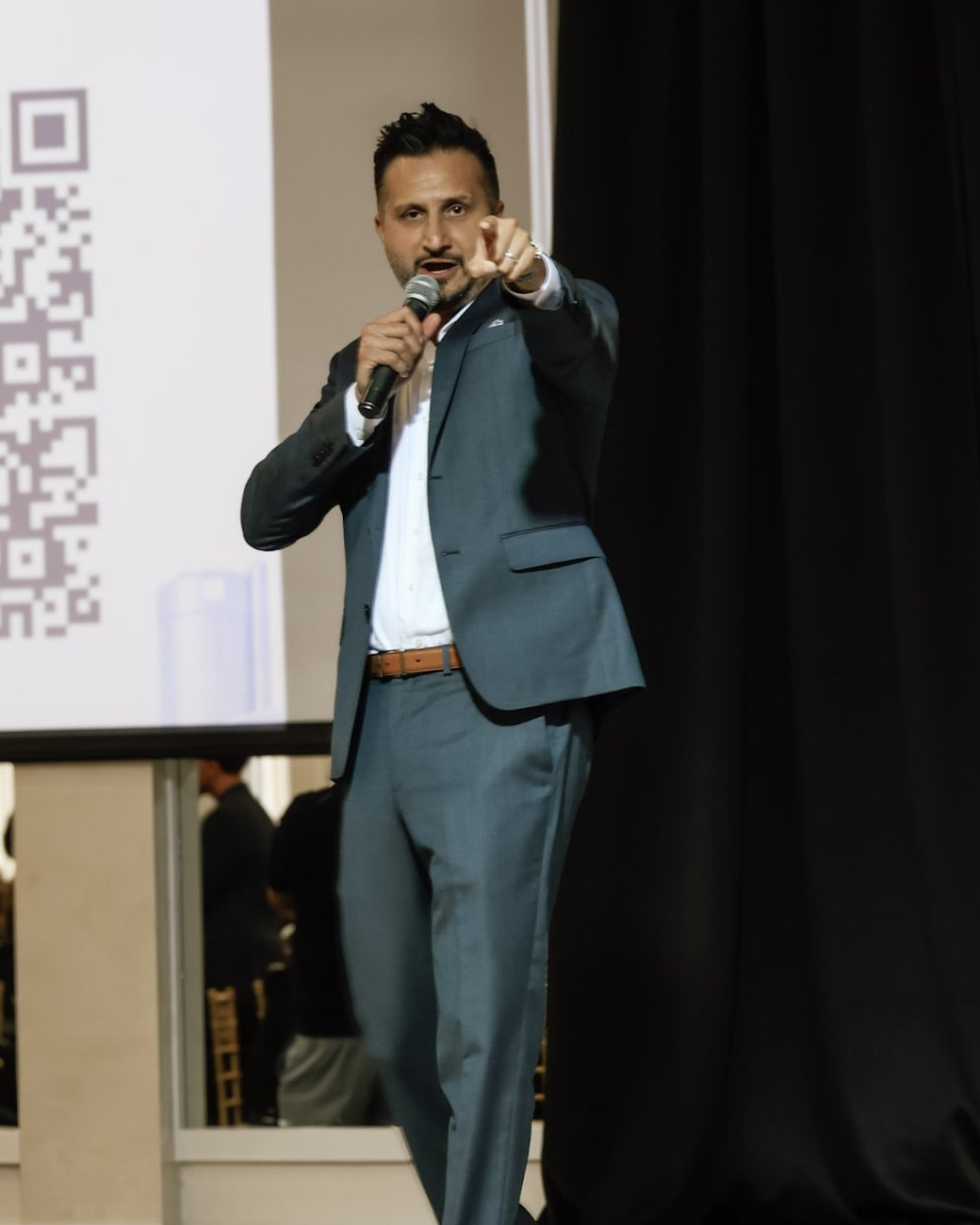 Asim Khan calling on a guest in the audience during the fundraising ask